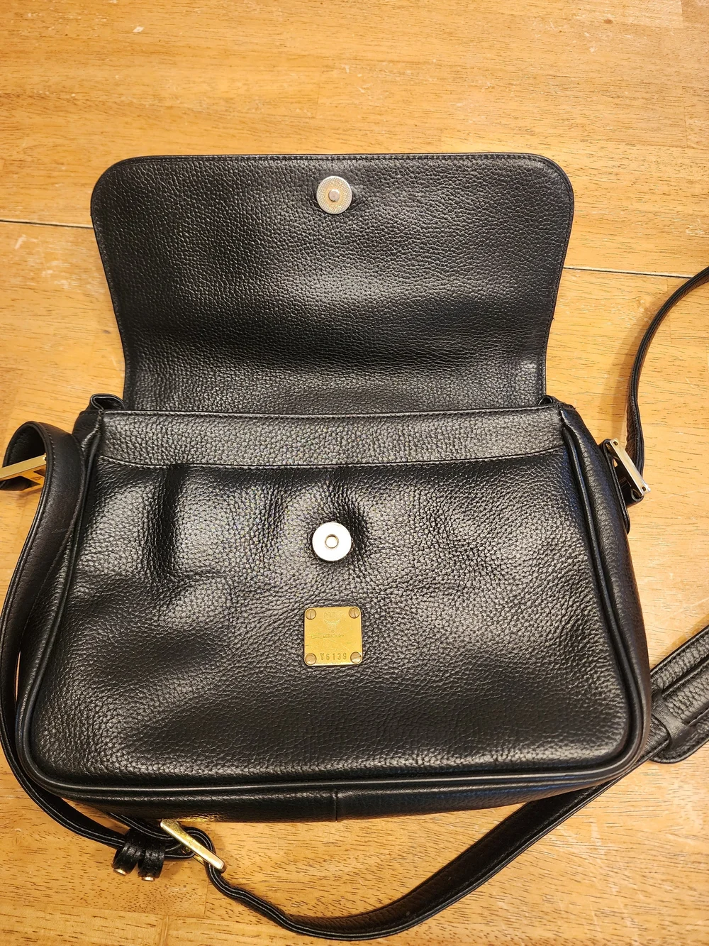 vintage MCM black pebbled leather studded crossbody bag featuring a front plaque